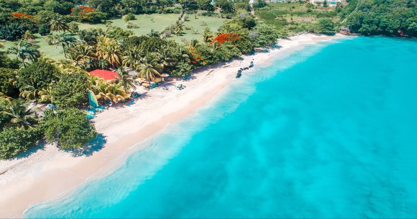 Widok z lotu ptaka na bujną zieloną tropikalną roślinność, biały piasek i turkusowy ocean na plaży Grand Anse, Morne Rouge, Grenada, Karaiby