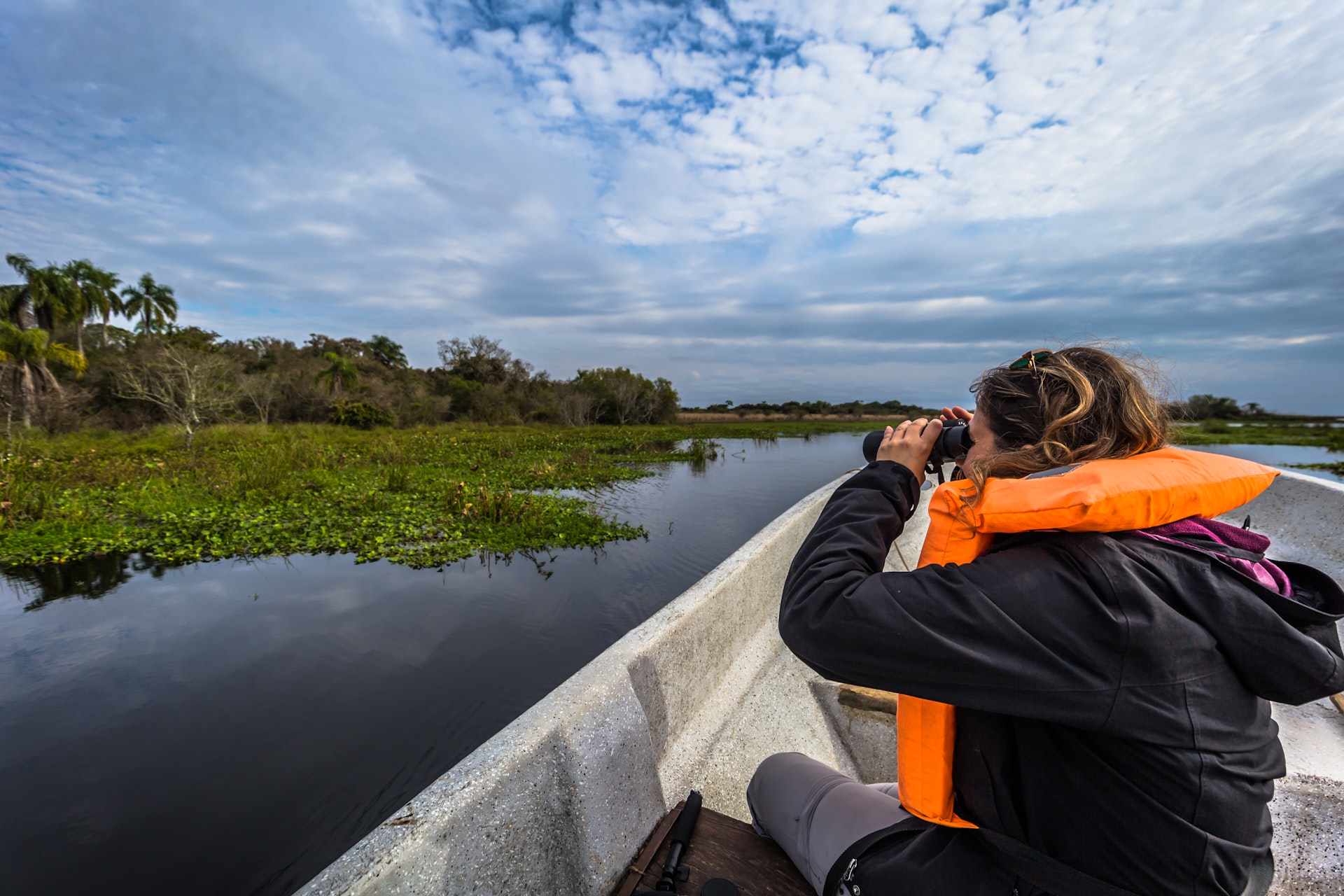 Podróżnik patrzy łodzią przez lornetkę w Parku Narodowym Iberá, Colonia Carlos Pellegrini, prowincja Corrientes, Argentyna