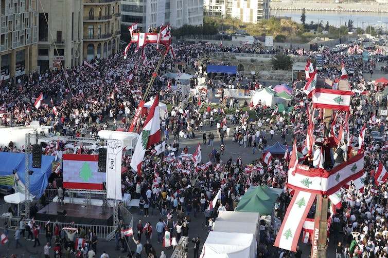 wielu protestujących maszeruje w centrum Bejrutu, niosąc libańskie flagi