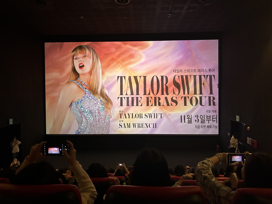 Fani Taylor Swift robią zdjęcia przed pokazem plakatów przed premierą „Taylor Swift: The Eras Tour” w piątek w CGV Yongsan. [SHIN MIN-HEE]