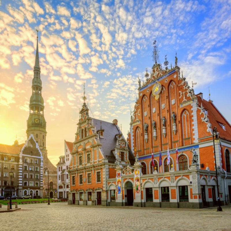 Plac Ratuszowy z Domem Czarnogłowych i kościołem Świętego Piotra na Starym Mieście w Rydze o dramatycznym wschodzie słońca, Łotwa