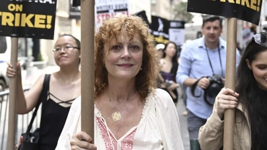 Susan Sarandon odbiera znak strajku.  Przed studiami Warner Bros. w Burbank w Kalifornii tłumy protestujących skandowały: „Pięści do góry, kurtyny opuszczone, Los Angeles to miasto związkowe”.  Food trucki stojące po obu stronach namiotów organizatorów serwowały churros, herbatę boba i zimną lemoniadę protestującym pieczącym w południowym upale sięgającym 36,7 stopni Celsjusza. 