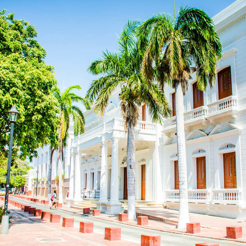 Budynek w stylu kolonialnym bielony, otoczony palmami w Santa Marta, na północnym wybrzeżu Kolumbii, w Ameryce Południowej