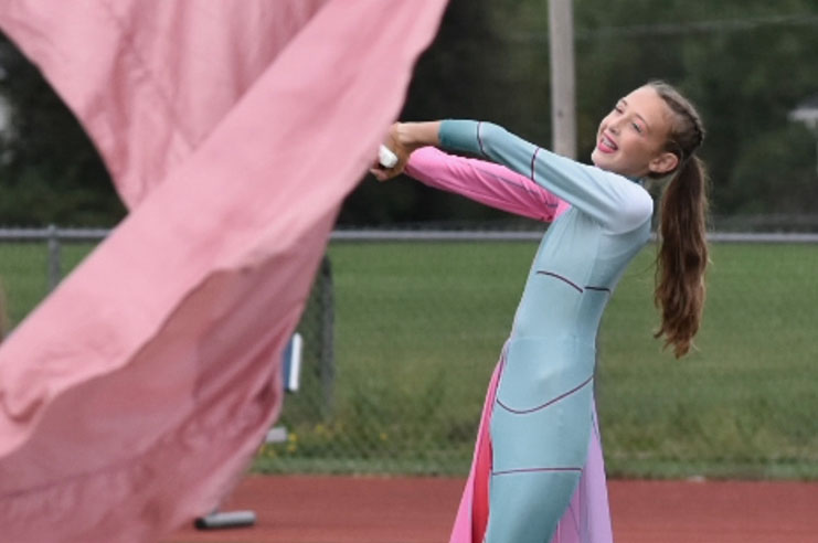 Chloe macha dużą różową flagą w ramach swojej roli w szkolnej drużynie straży kolorowej.