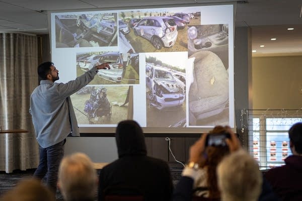 Mężczyzna wskazuje na zdjęcia uszkodzonego samochodu wyświetlane na ekranie