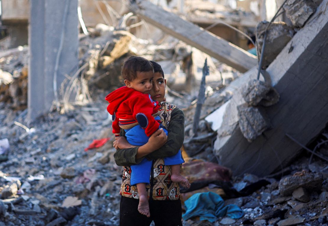 Palestyński chłopiec z dzieckiem stoi w miejscu izraelskich ataków, pośród trwającego konfliktu między Izraelem a palestyńską grupą Hamas, w Rafah, w południowej Strefie Gazy, 4 grudnia 2023 r. REUTERS/Mohammed Salem REFILE – QUALITY REPEAT TPX OBRAZY DNIA