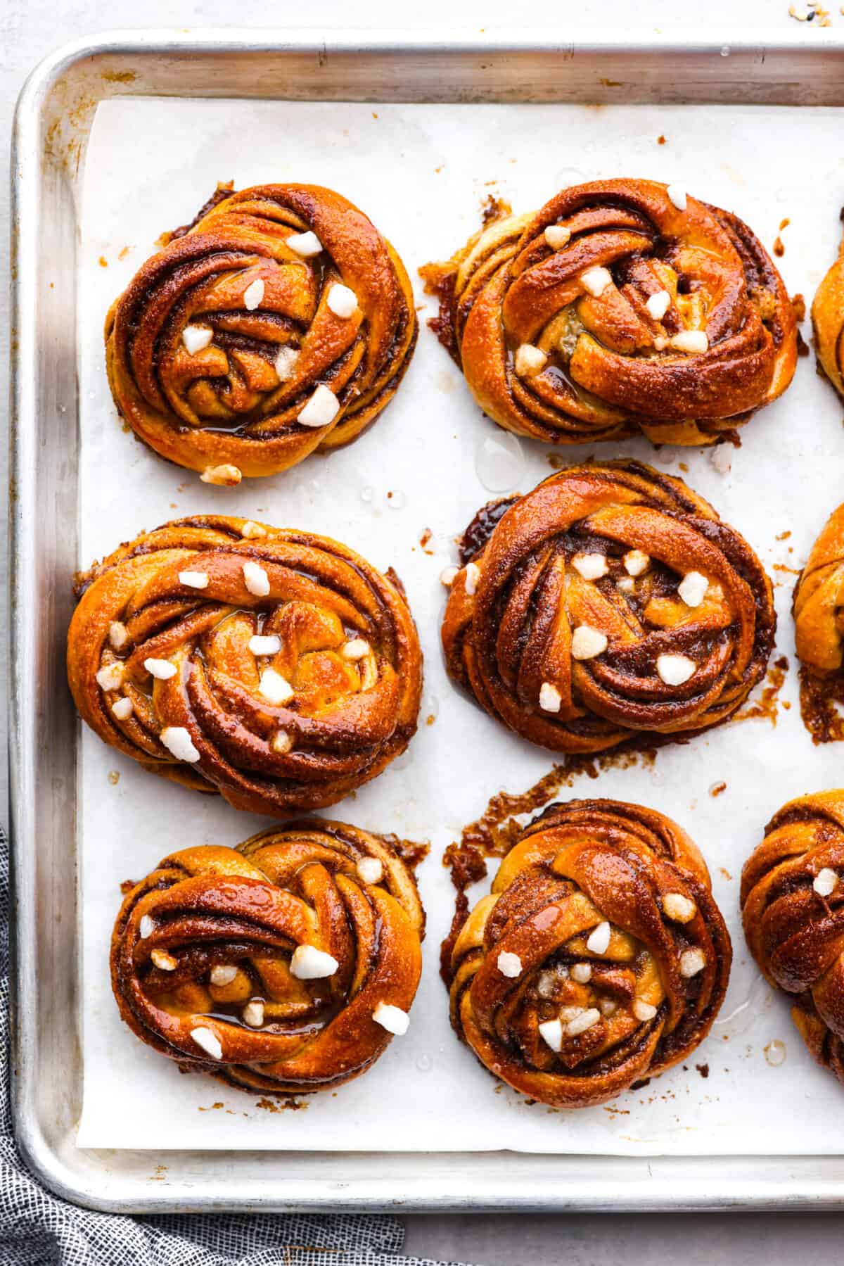 Kanelbullar na blasze wyłożonej papierem do pieczenia.