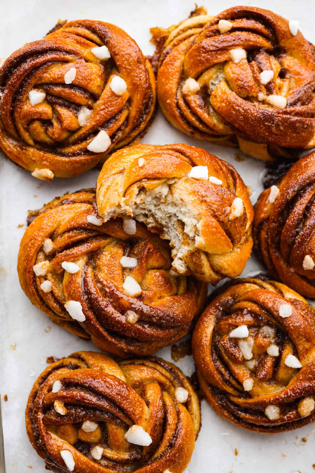 Zbliżenie bułeczek kanelbullar posypanych cukrem perłowym.  Jedna jest rozdarta na pół.