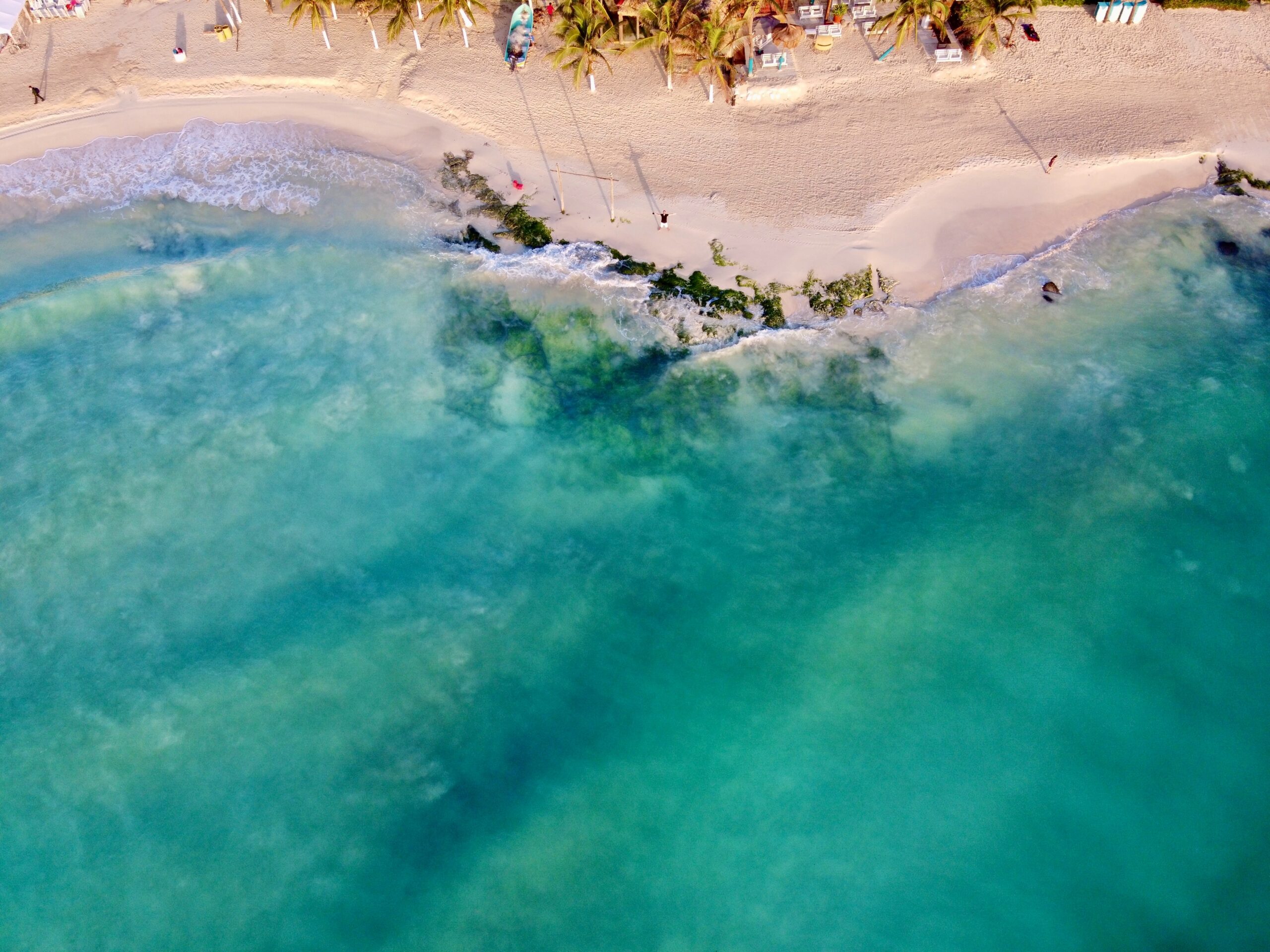 Playa del Carmen to wymarzone miejsce dla podróżników pragnących spędzić spokojne, ale pełne wrażeń wakacje na plaży.  Na zdjęciu: turkusowa plaża Playa del Carmen z brązowym piaskiem 