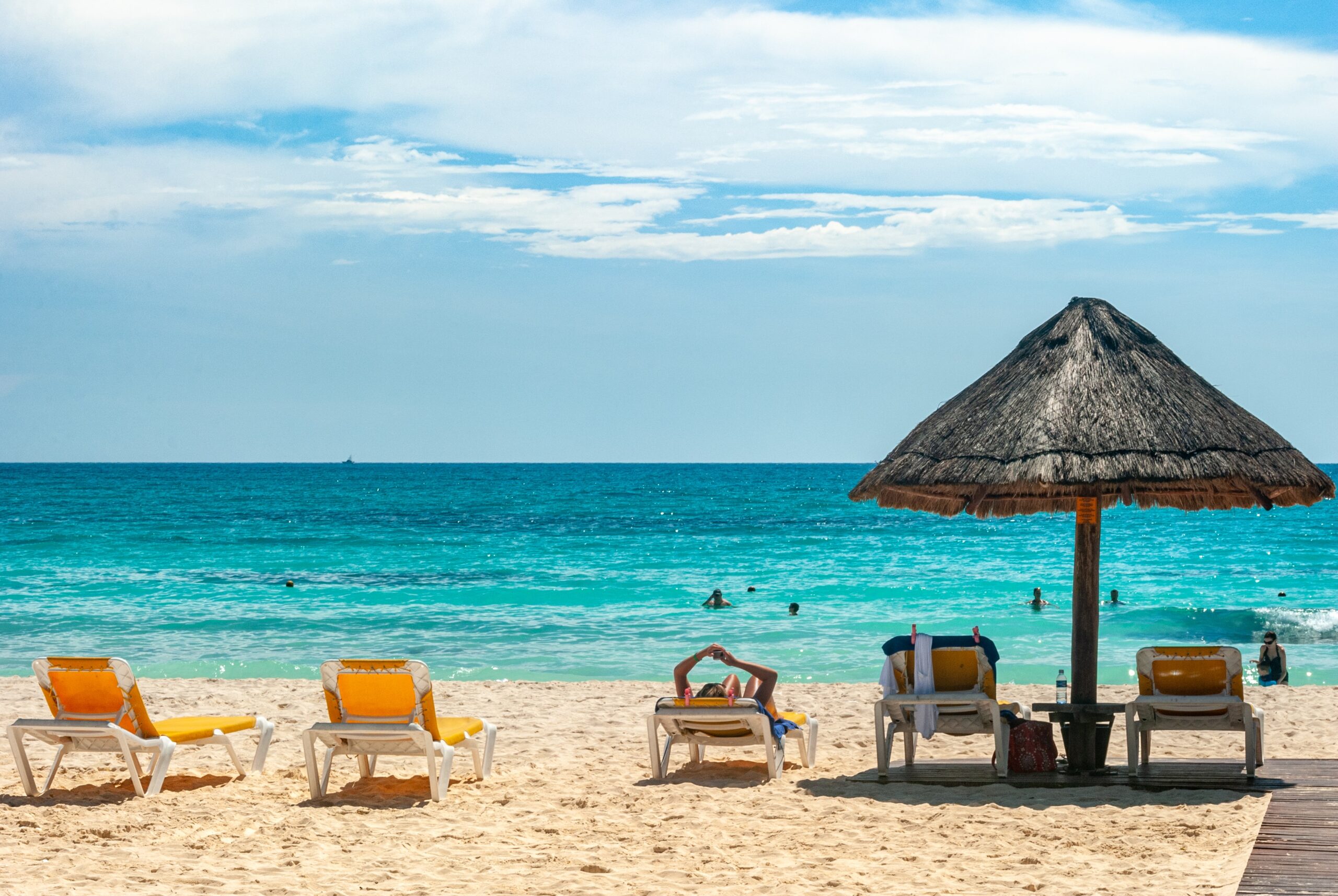 Cancun to bardzo popularne miejsce w Meksyku, uważane za bezpieczne miejsce do odwiedzenia.  Na zdjęciu: plaża w Cancun z leżakami na ciepłym piasku i przejrzystą, błękitną wodą 