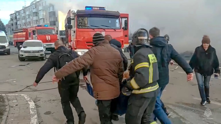 Ratownicy i ludzie niosą rannego po ostrzale w Biełgorodzie