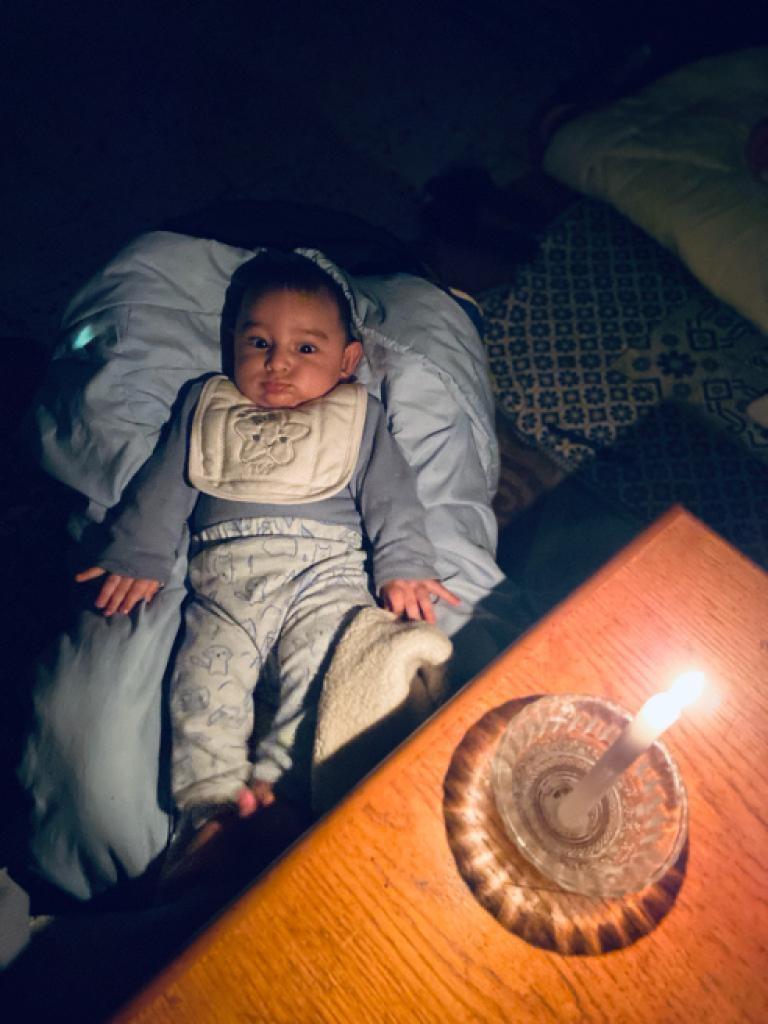 Pięciomiesięczne dziecko autorki i świeca u jej boku [Maram Humaid/Al Jazeera]