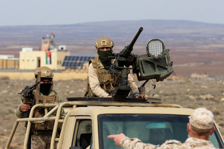 Jordański żołnierz stoi z tyłu wojskowej ciężarówki, za zamontowanym karabinem maszynowym.