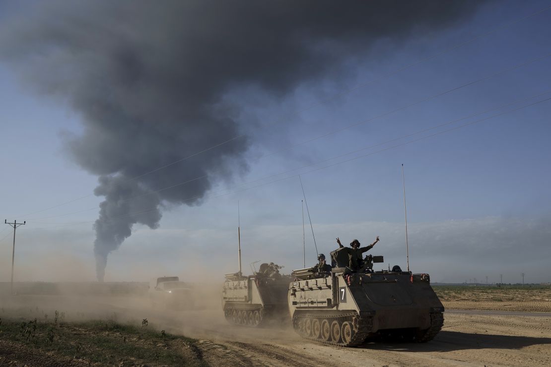Izraelscy żołnierze przemieszczają się na transporterach opancerzonych (APC) w pobliżu granicy izraelsko-Gaza, gdy dym unosi się w niebo w Strefie Gazy, widziany z południowego Izraela, niedziela, 21 stycznia 2024 r. (AP Photo/Leo Correa)