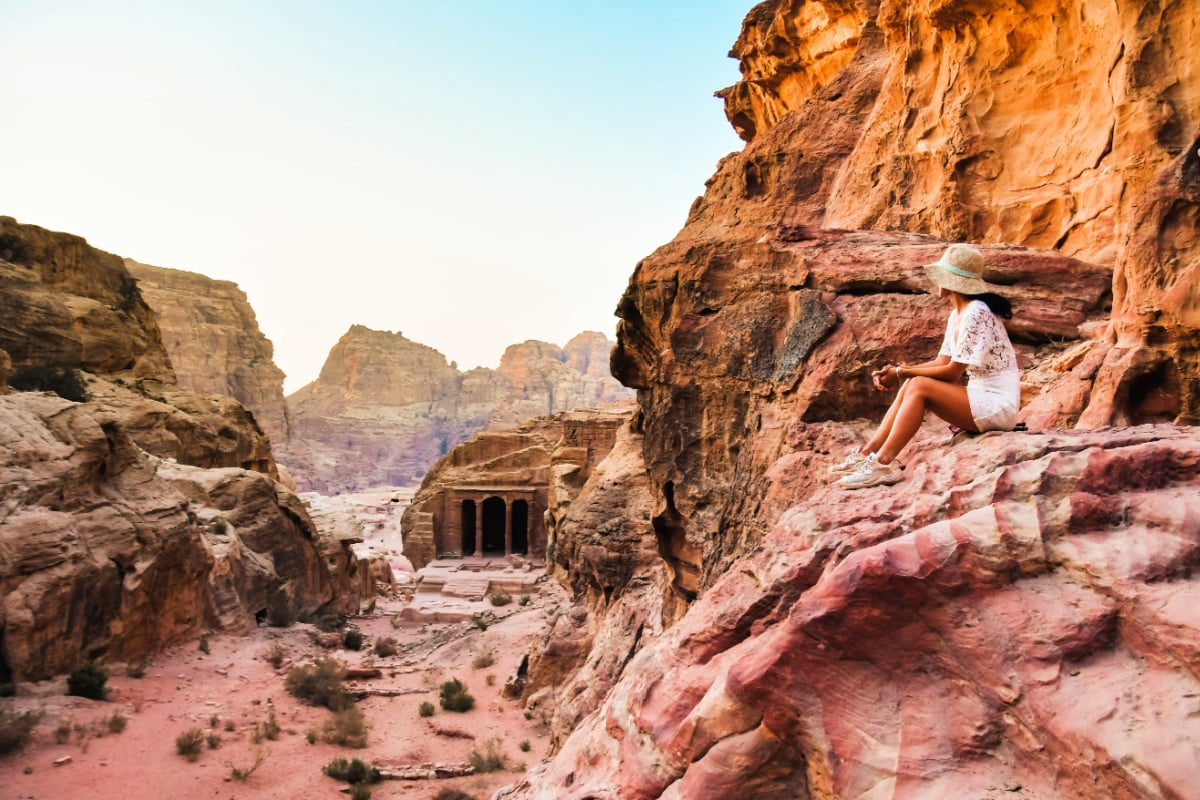 Kobieta podróżująca turystka siedząca na punkcie widokowym w starożytnym mieście Petra, starożytnym miejscu historycznym, słynnym celu podróży w Jordanii i jednym z siedmiu cudów.  Miejsce światowego dziedzictwa UNESCO