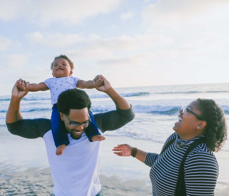 czarna rodzina na plaży śmieje się z dzieckiem