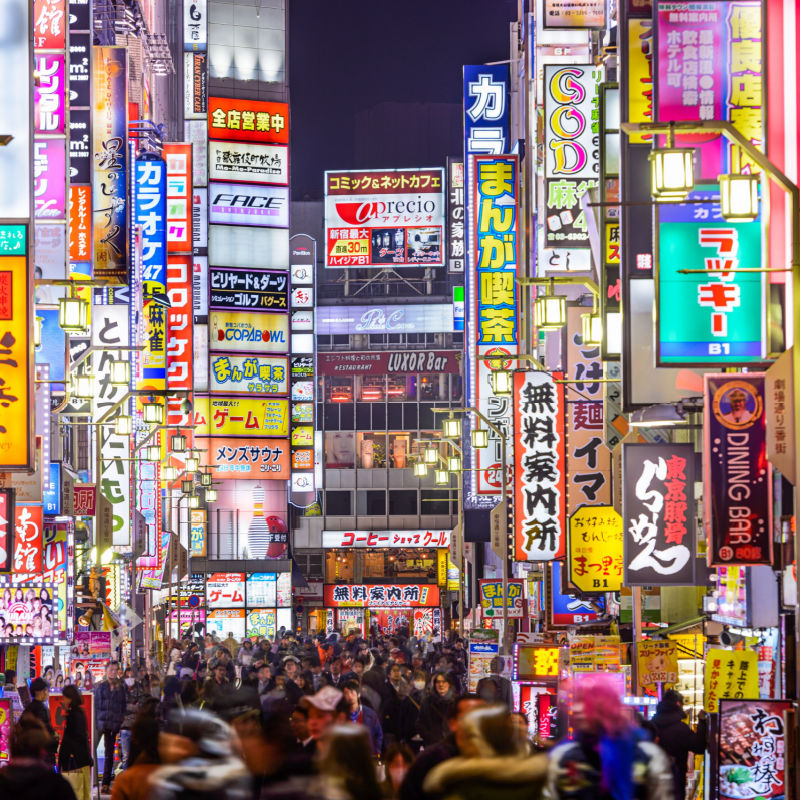 Ruchliwa ulica w Tokio jest oświetlona wieloma jasnymi znakami, Japonia