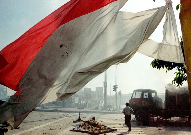 Postrzępiona flaga Indonezji i spalony samochód w pobliżu Trisakti w maju 1998 r