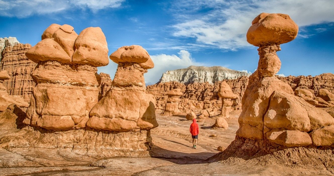 Panoramiczny widok na mężczyznę wędrującego pośród oszałamiających formacji piaskowca Hoodoos w słynnym parku stanowym Goblin Valley w stanie Utah