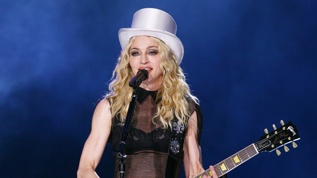 Madonna na koncercie ma na sobie biały cylinder i gra na gitarze