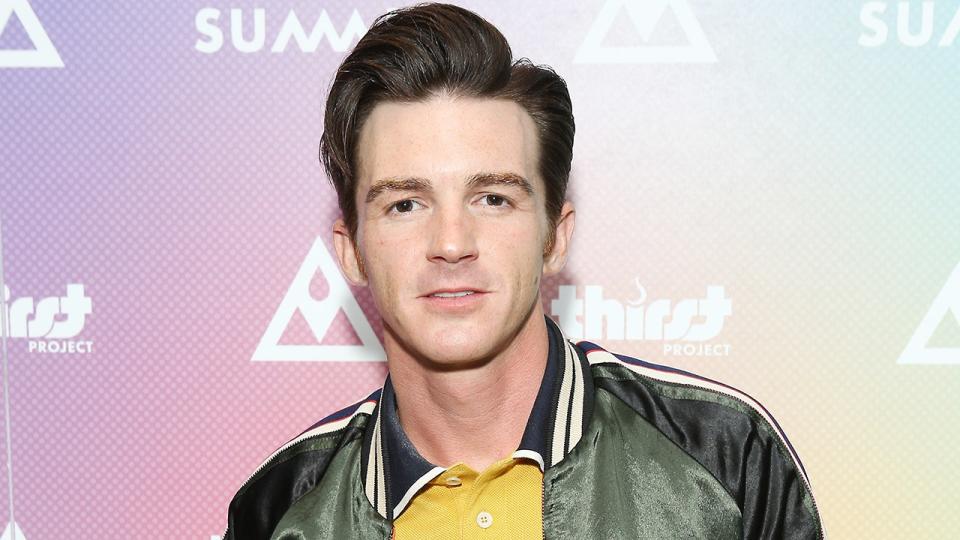 Drake Bell na czerwonym dywanie ma na sobie zieloną kurtkę i żółtą koszulę z kołnierzykiem w niebieskie paski