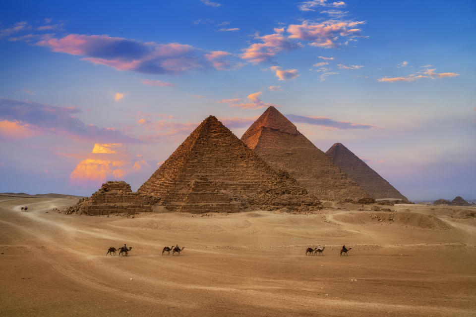 Trzy piramidy w Egipcie z ludźmi na wielbłądach na pierwszym planie