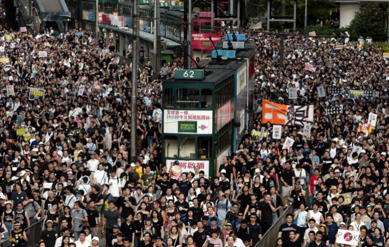 Masowy protest w Hongkongu w 2003 r. w związku z planowaną ustawą o bezpieczeństwie.  Pośrodku tłumu stoi piętrowy autobus