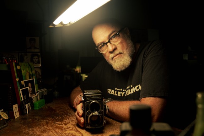 Dan siedzi przy biurku ze starym aparatem Rolleiflex.  (National Geographic/David Fausto)