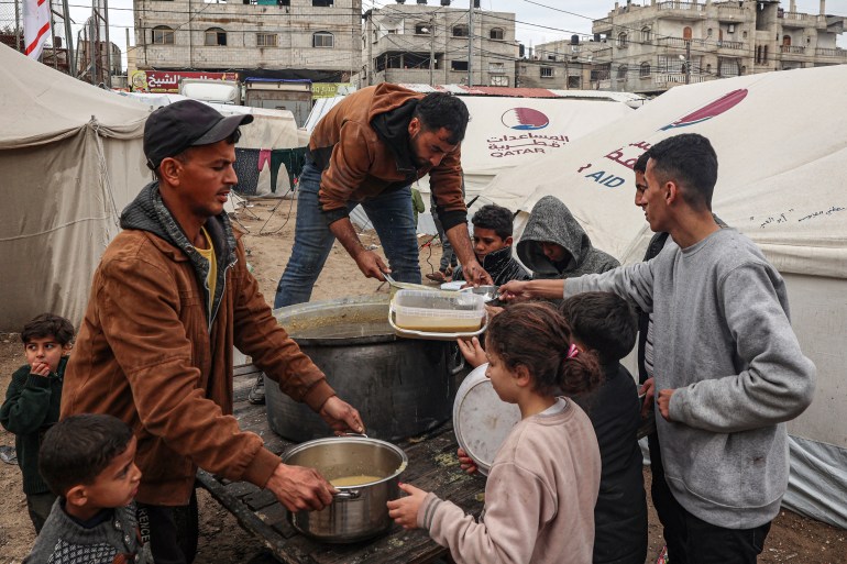 Wolontariusze rozdają racje zupy z czerwonej soczewicy wysiedlonym Palestyńczykom w Rafah w południowej Strefie Gazy, 18 lutego 2024 r.