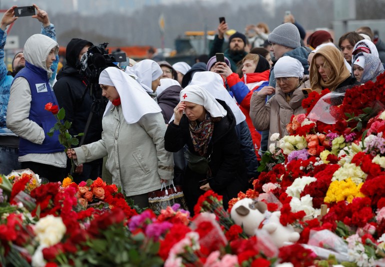 Ludzie składają kwiaty pod prowizorycznym pomnikiem ofiar strzelaniny ustawionym przed salą koncertową Crocus City Hall w obwodzie moskiewskim, Rosja, 24 marca 2024 r. REUTERS/Maxim Shemetov