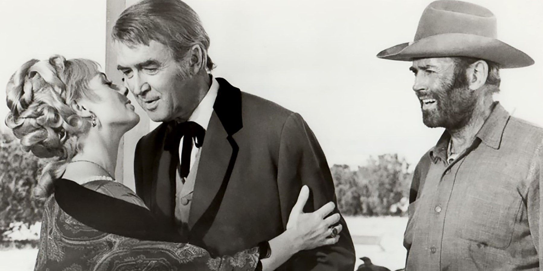 James Stewart jako John O'Hanlan, Henry Fonda jako Harley Sullivan i Shirley Jones jako Jenny pochylająca się, by pocałować Johna w policzek w „The Cheyenne Social Club”