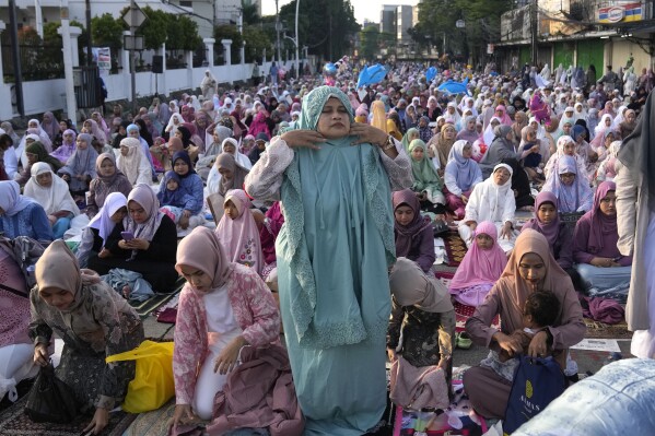Muzułmanka zakłada szatę do modlitwy podczas modlitwy Id al-Fitr na zakończenie świętego miesiąca postu Ramadan, Dżakarta, Indonezja, środa, 10 kwietnia 2024 r. (AP Photo/Dita Alangkara)