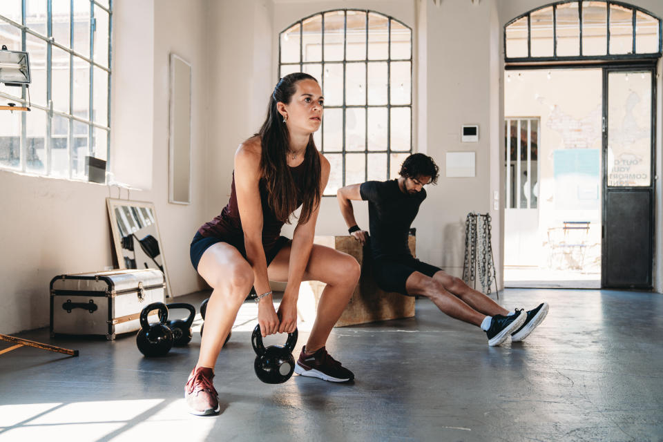 Obwód treningu przekrojowego w klubie fitness na poddaszu przemysłowym z dużymi oknami.