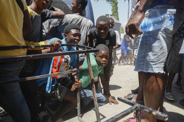 PLIK – Młodzież ukrywa się po usłyszeniu strzałów w szkole publicznej, która służy jako schronienie dla osób wysiedlonych w wyniku przemocy gangów, w Port-au-Prince, Haiti, 22 marca 2024 r. (AP Photo/Odelyn Joseph, plik)