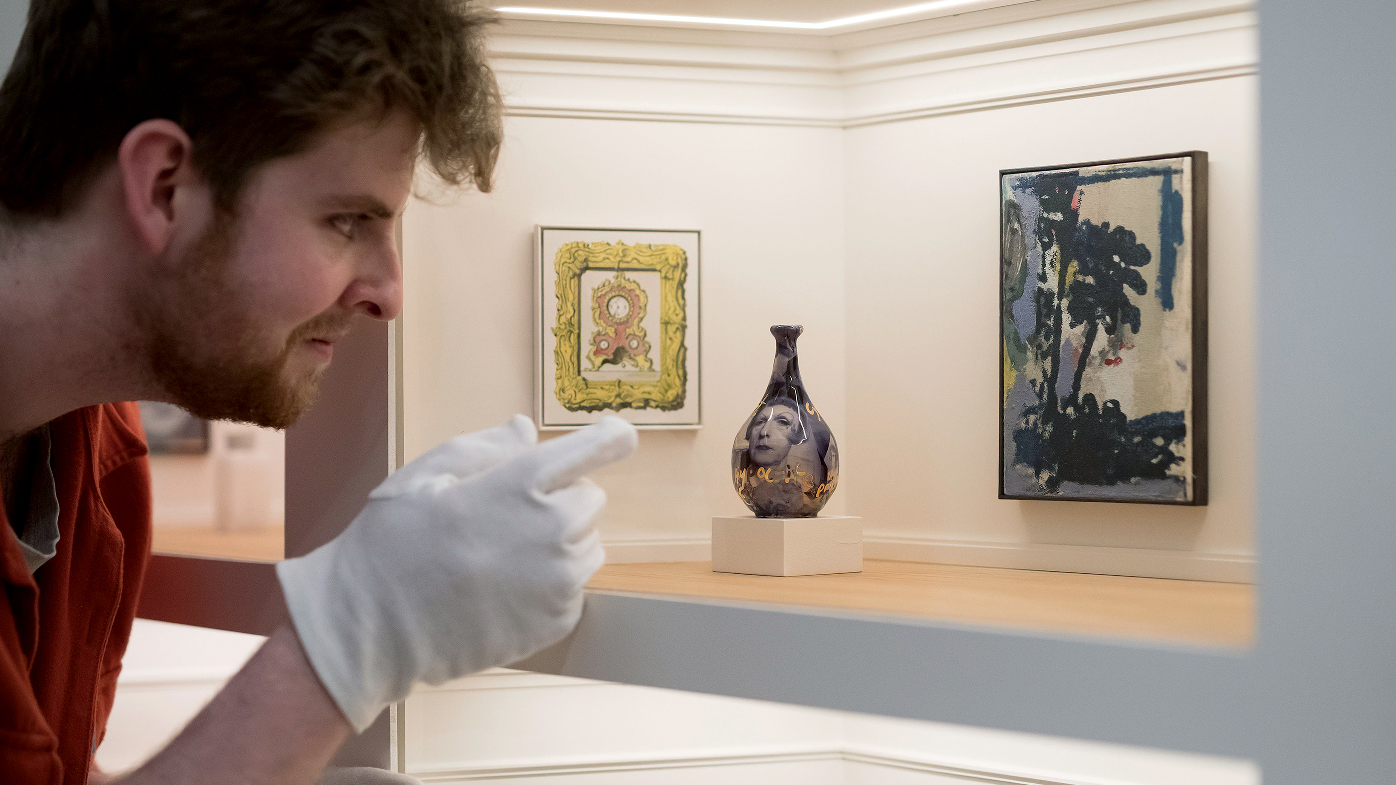 Mężczyzna w rękawiczkach ogląda wystawę w galerii sztuki modelarskiej, w której znajduje się 80 oryginalnych miniaturowych dzieł sztuki