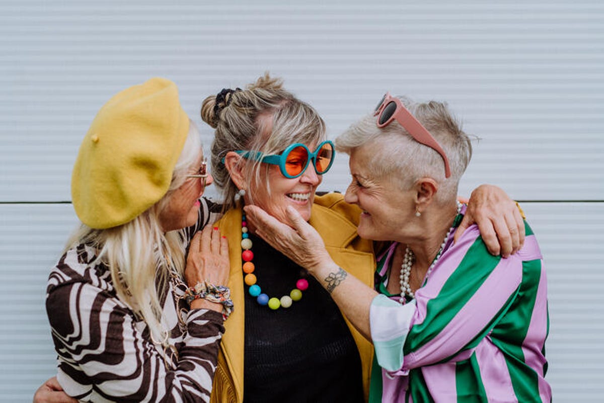 Trzy szczęśliwe starsze kobiety ubrane w kolorowe ubrania.