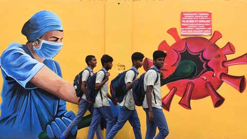 Uczniowie bez masek przechodzą obok muralu przedstawiającego COVID-19 w Korukkupet w Chennai.  (BA Raju/TOI, BCCL, Chennai)