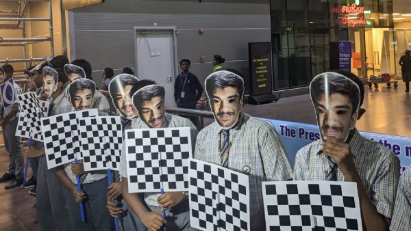 Uczniowie w maskach Gukesha na lotnisku w Chennai czekają na powitanie 17-latka