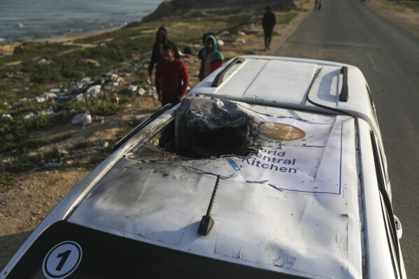 PLIK – Palestyńczycy sprawdzają pojazd z logo World Central Kitchen zniszczony przez izraelski nalot w Deir al Balah w Strefie Gazy 2 kwietnia 2024 r. (AP Photo/Ismael Abu Dayyah, plik)