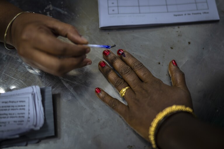 Urzędnik wyborczy kładzie niezatarty ślad atramentem na palcu wskazującym kobiety przybywającej do głosowania podczas pierwszej tury głosowania w wyborach krajowych w Indiach w Chennai, w południowym stanie Tamil Nadu, piątek, 19 kwietnia 2024 r. Prawie 970 milionów wyborców wybierze 543 członków izby niższej parlamentu na pięcioletnią kadencję w rozłożonych w czasie wyborach, które potrwają do 1 czerwca. (AP Photo/Altaf Qadri)