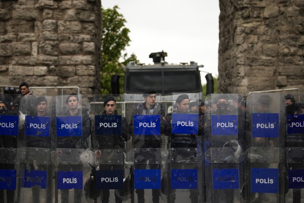 Funkcjonariusze policji walczący z zamieszkami stoją na straży, blokując drogę protestującym podczas marszu członków związku podczas obchodów Święta Pracy w Stambule w Turcji, środa, 1 maja 2024 r. Policja w Stambule zatrzymała dziesiątki osób, które próbowały dotrzeć na główny plac miasta, Taksim, w wbrew rządowemu zakazowi obchodzenia Święta Pracy 1 maja w charakterystycznym miejscu.  (AP Photo/Emrah Gurel)