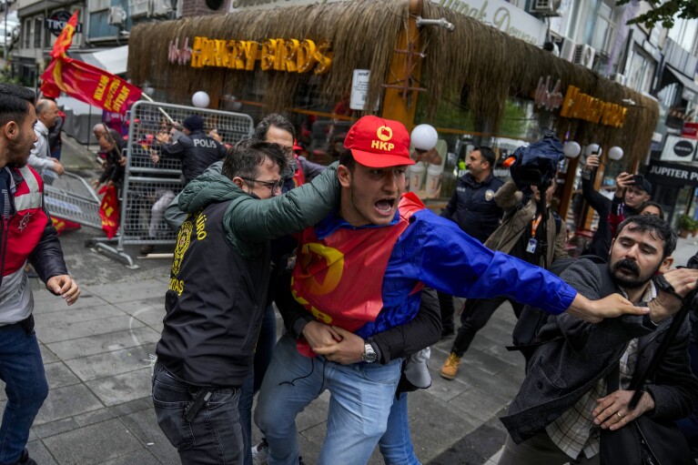 Członek związku kłóci się z policjantami w cywilu, maszerując z innymi podczas obchodów Święta Pracy w Stambule, Turcja, środa, 1 maja 2024 r. (AP Photo/Khalil Hamra)