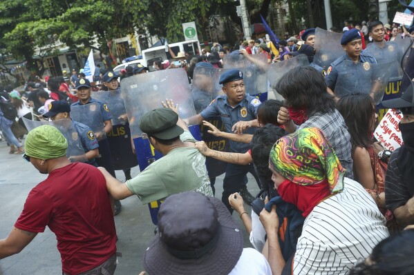 Policjanci próbują blokować aktywistów, którzy próbowali maszerować w stronę ambasady USA podczas protestu z okazji Międzynarodowego Święta Pracy w Manili na Filipinach w środę, 1 maja 2024 r. Setki filipińskich pracowników z różnych grup zawodowych wyszło na ulice, aby uczcić Święto Pracy oraz żądać podwyżki płac i bezpieczeństwa pracy w obliczu gwałtownie rosnących cen żywności i ropy.  (AP Photo/Basilio Sepe)