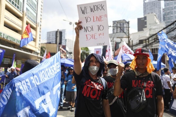 Mężczyzna niesie plakat podczas protestu z okazji Międzynarodowego Święta Pracy w pobliżu pałacu prezydenckiego w Manili na Filipinach, środa, 1 maja 2024 r. Setki filipińskich pracowników z różnych grup zawodowych wyszło na ulice, aby uczcić Święto Pracy i domagać się podwyżki płac i bezpieczeństwo pracy w obliczu gwałtownie rosnących cen żywności i ropy.  (AP Photo/Basilio Sepe)