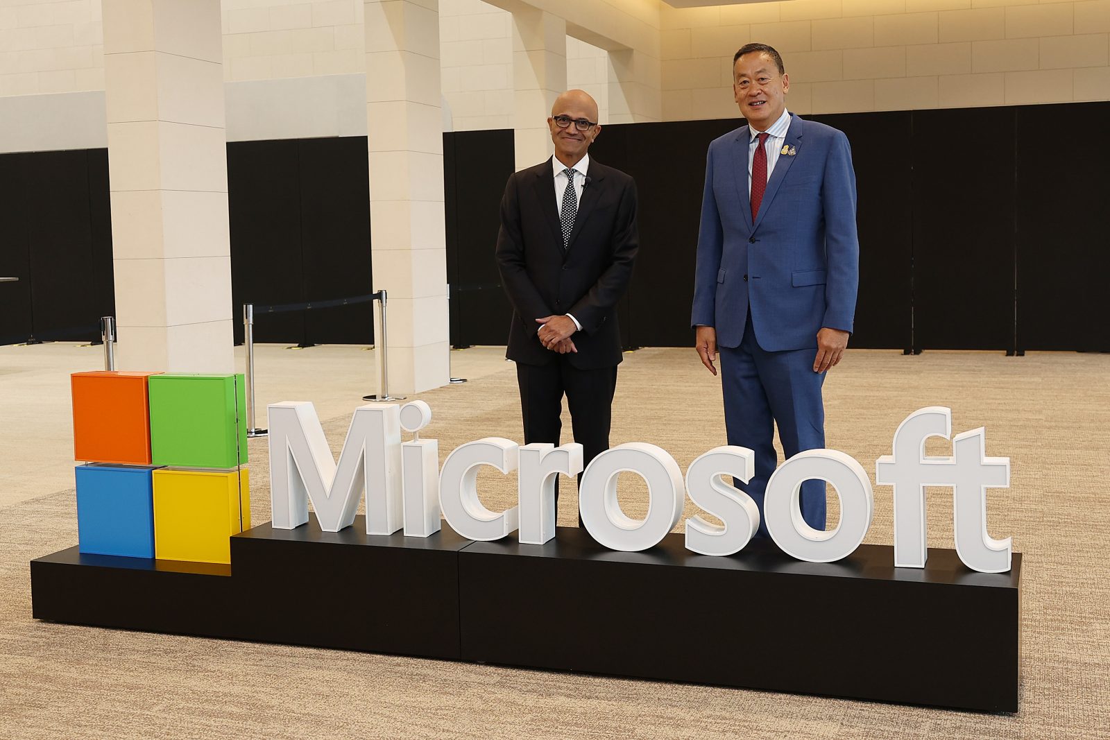 Dwóch mężczyzn pozujących za logo Microsoftu
