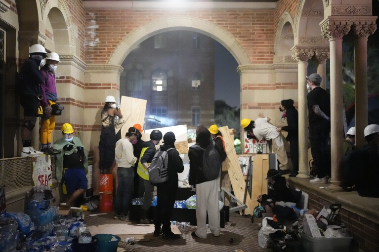 Propalestyńscy demonstranci obserwują działania policji za prowizoryczną barykadą na kampusie UCLA, środa, 1 maja 2024 r., Los Angeles.  (AP Photo/Jae C. Hong)