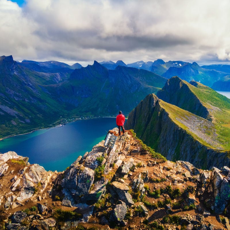 Turysta stojący na szczycie góry Husfjellet na wyspie Senja w północnej Norwegii, Nordland