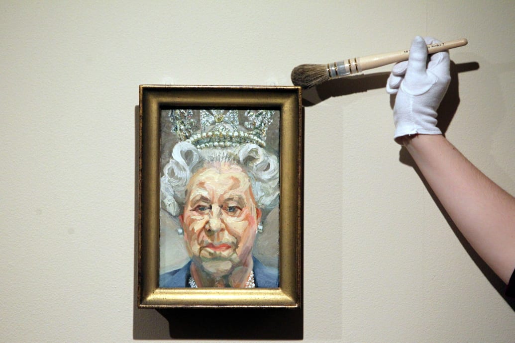 Kuratorka Lauren Porter odkurza portret królowej Elżbiety II autorstwa Luciana Freuda w ramach wystawy Królowa: portrety monarchy prezentowanej w zamku Windsor.