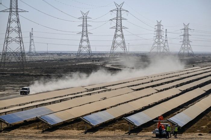 Pracownicy instalują panele słoneczne w parku energii odnawialnej Adani Group w Khavda w Indiach