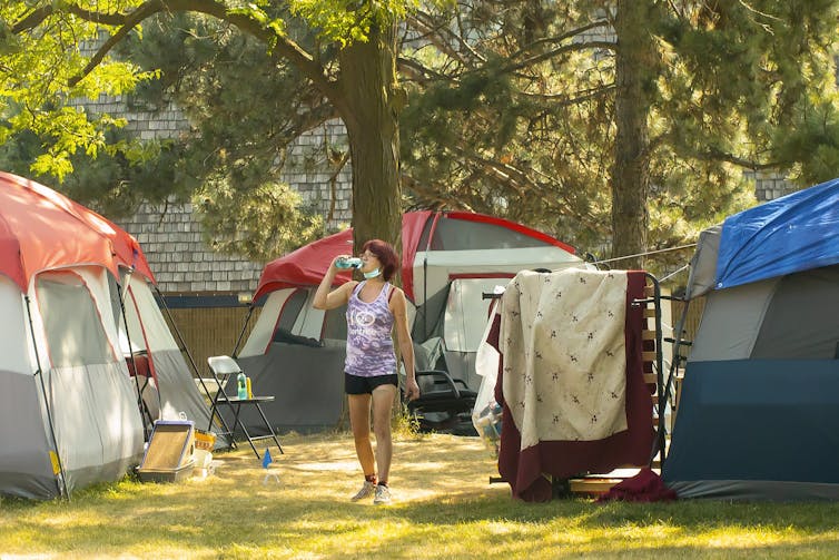 Kobieta w szortach stojąca wśród namiotów